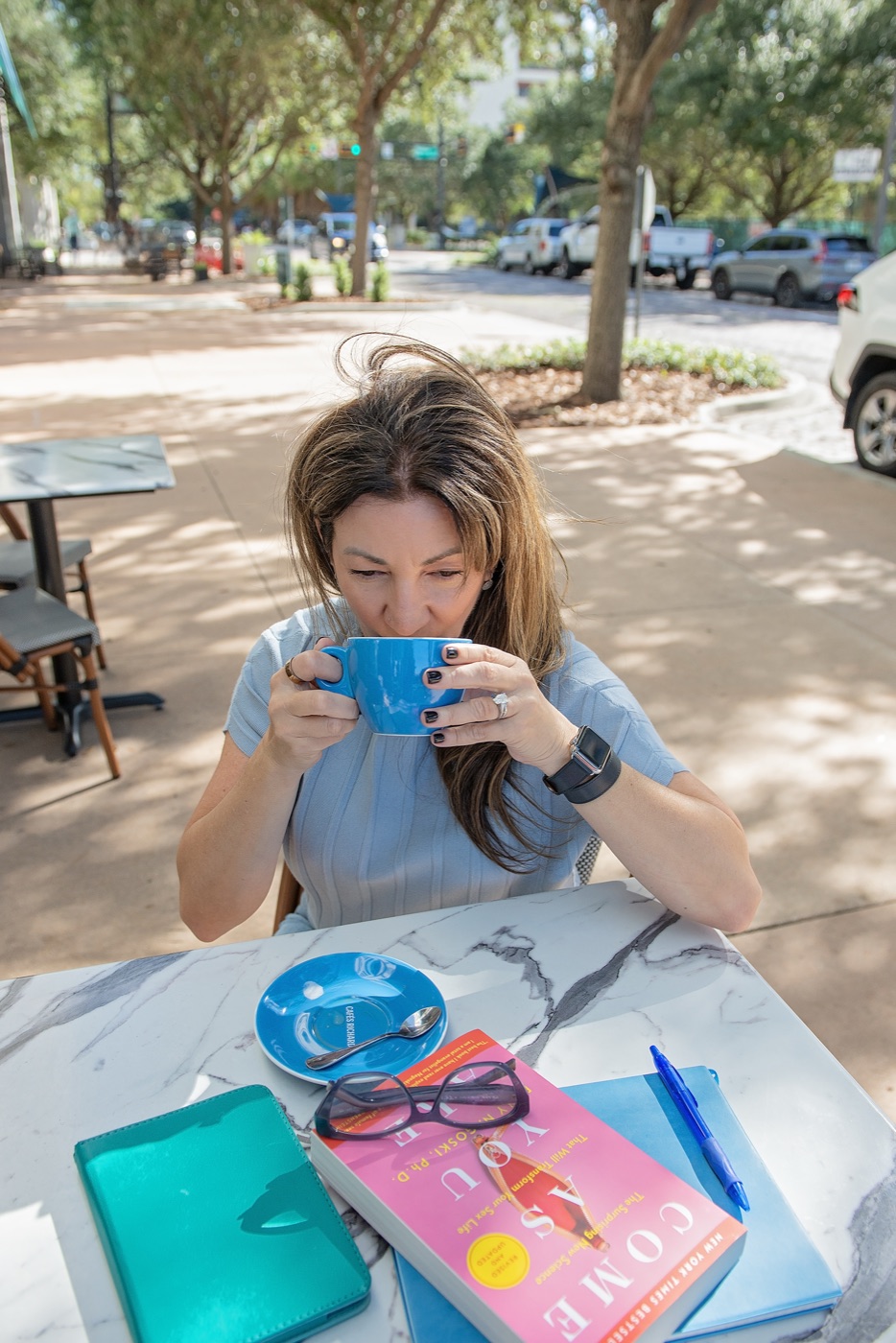Carrie in a soft wrap, holding a coffee cup and smiling