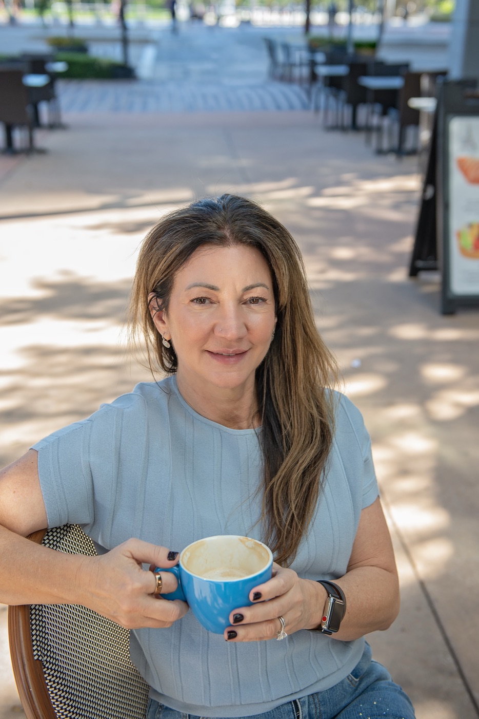Carrie smiling at an outdoor cafe