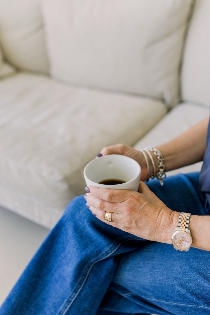 Carrie holding a cup of coffee on the sofa