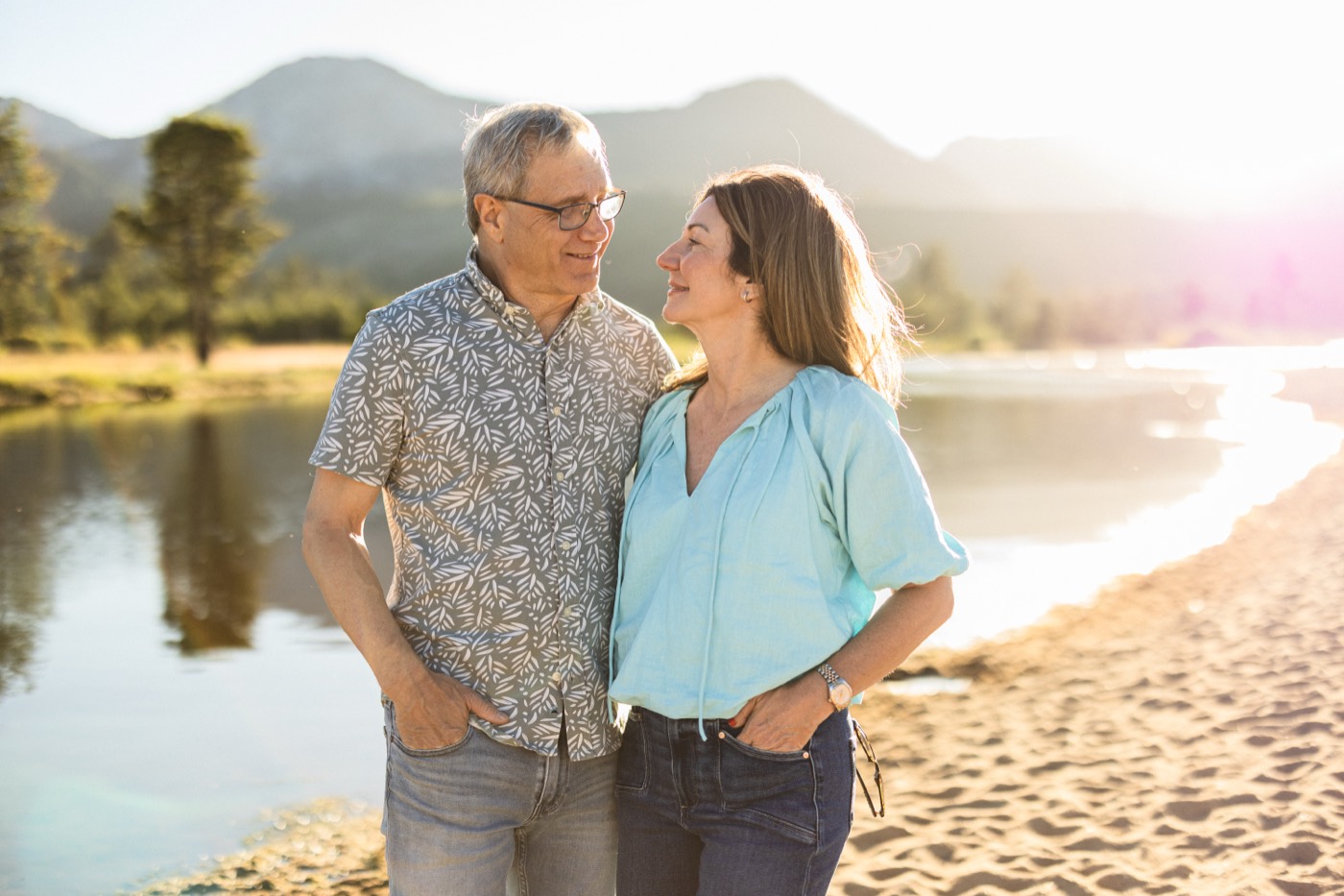 Carrie and her husband close together by a mountain lake